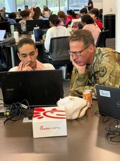 Commanding General Janovic helping student on computer during Parons Capture the Flag event at Georgia Cyber Center