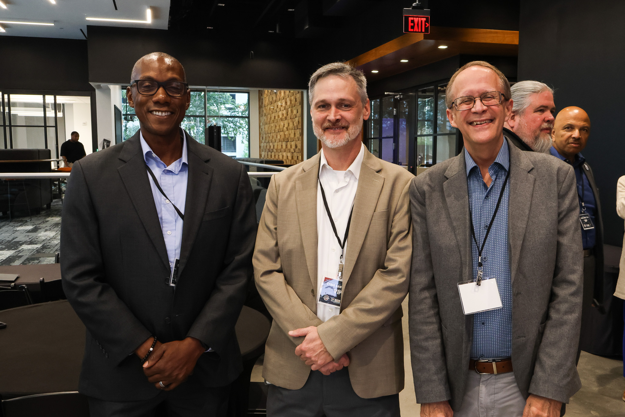 3 Cyber Dawg attendees (males) smiling at the camera in Georgia Cyber Center lobby