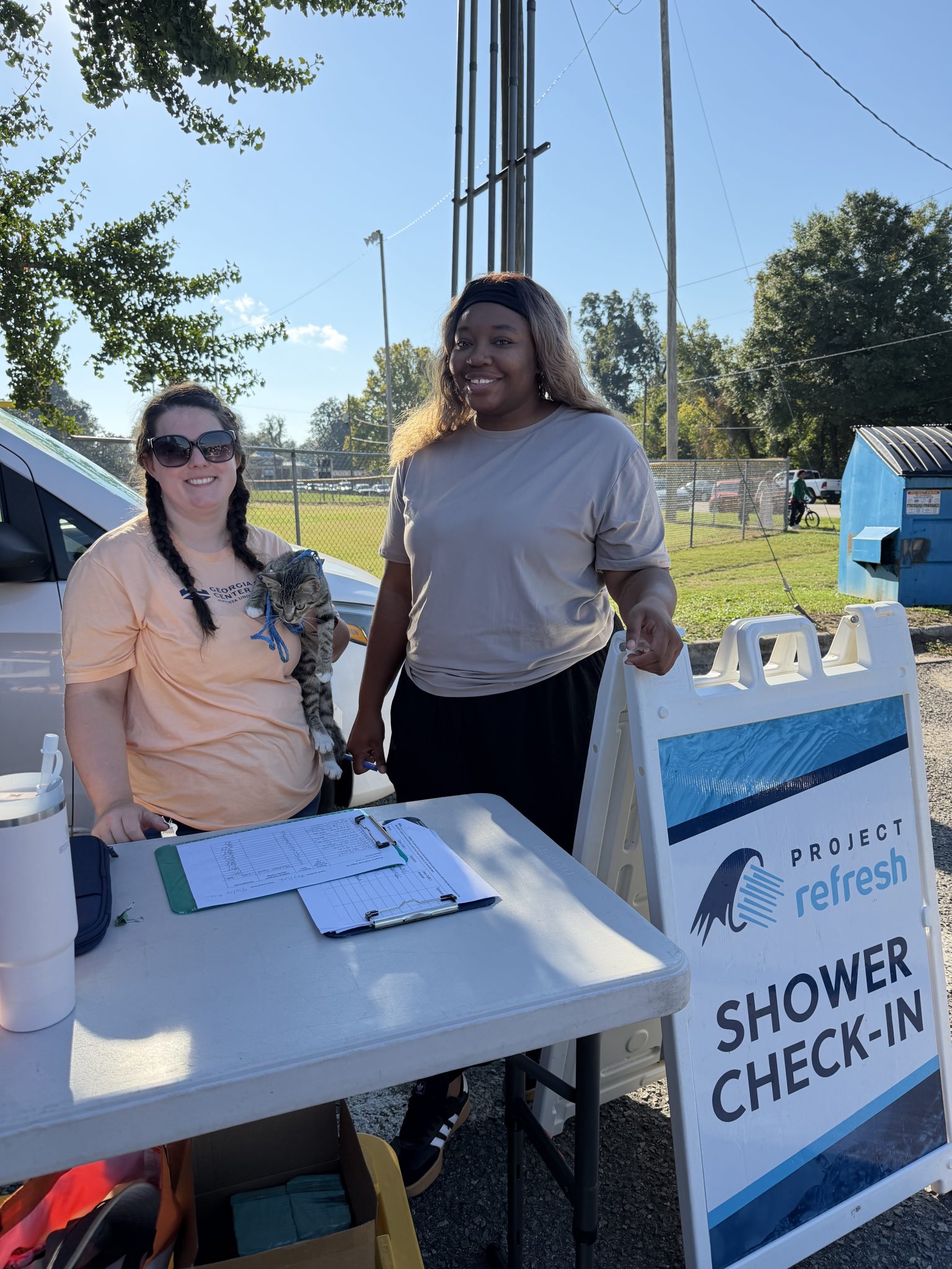 Georgia Cyber Center volunteers working Project Refresh sign in table at outdoor mobile showering event