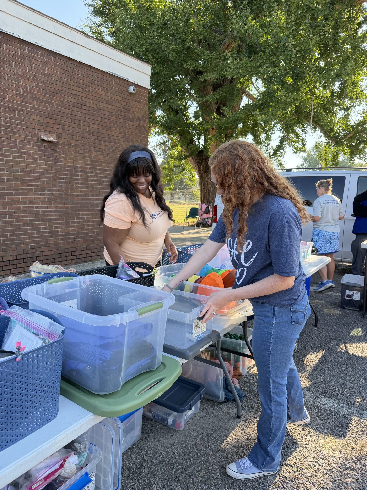 Georgia Cyber Center volunteers packing hygiene kits and clothing baskets for unhoused population at May Park