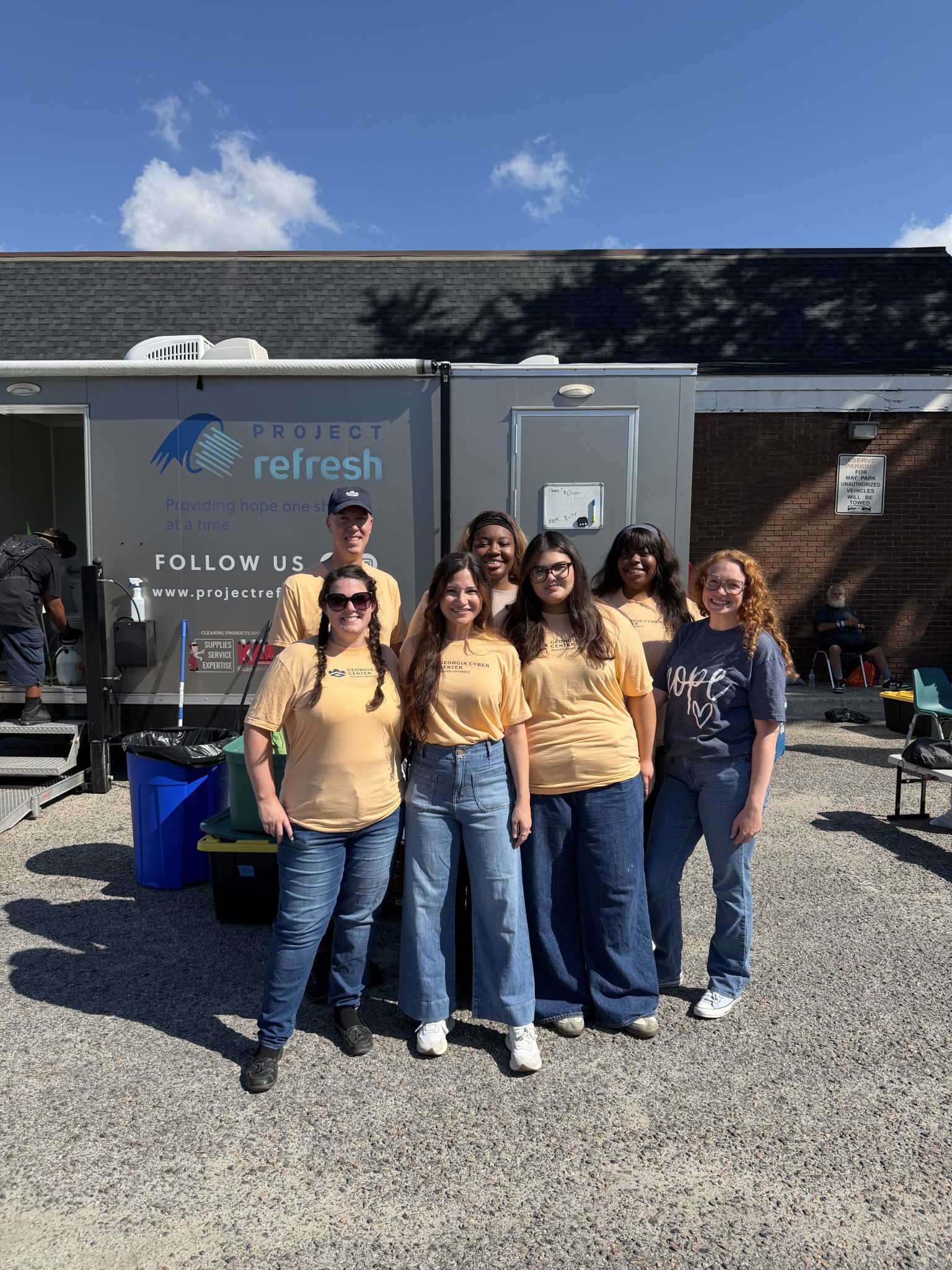 Georgia Cyber Center volunteers standing in front of Project Refresh mobile shower trailer at May Park